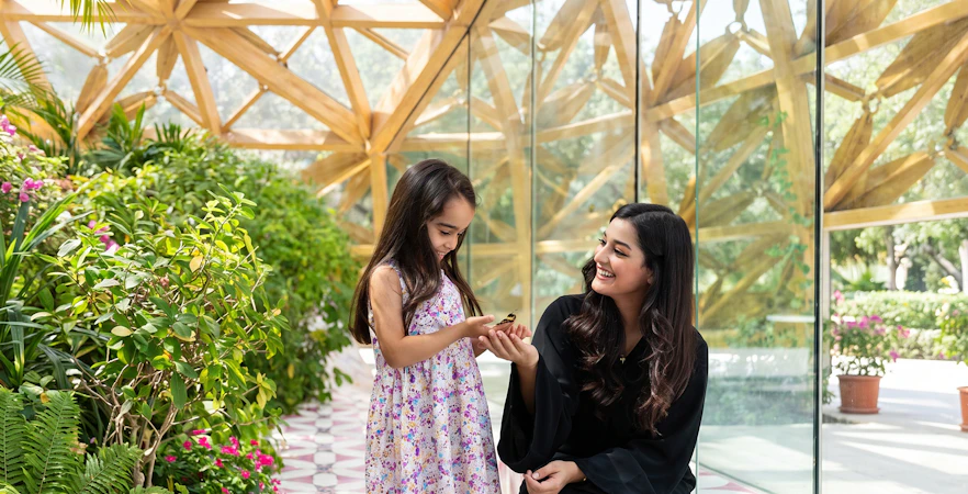 Child and woman enjoying butterfly at Al Noor Island Butterfly House.