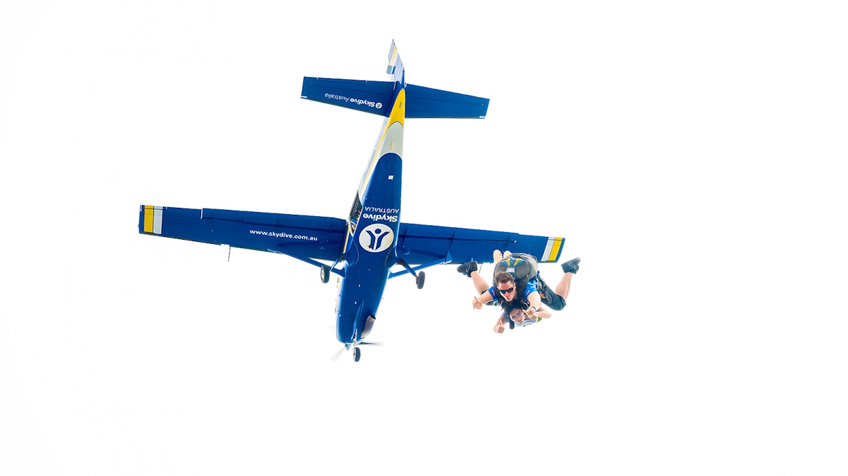 An instructor and a guest jumping off a plane to skydive