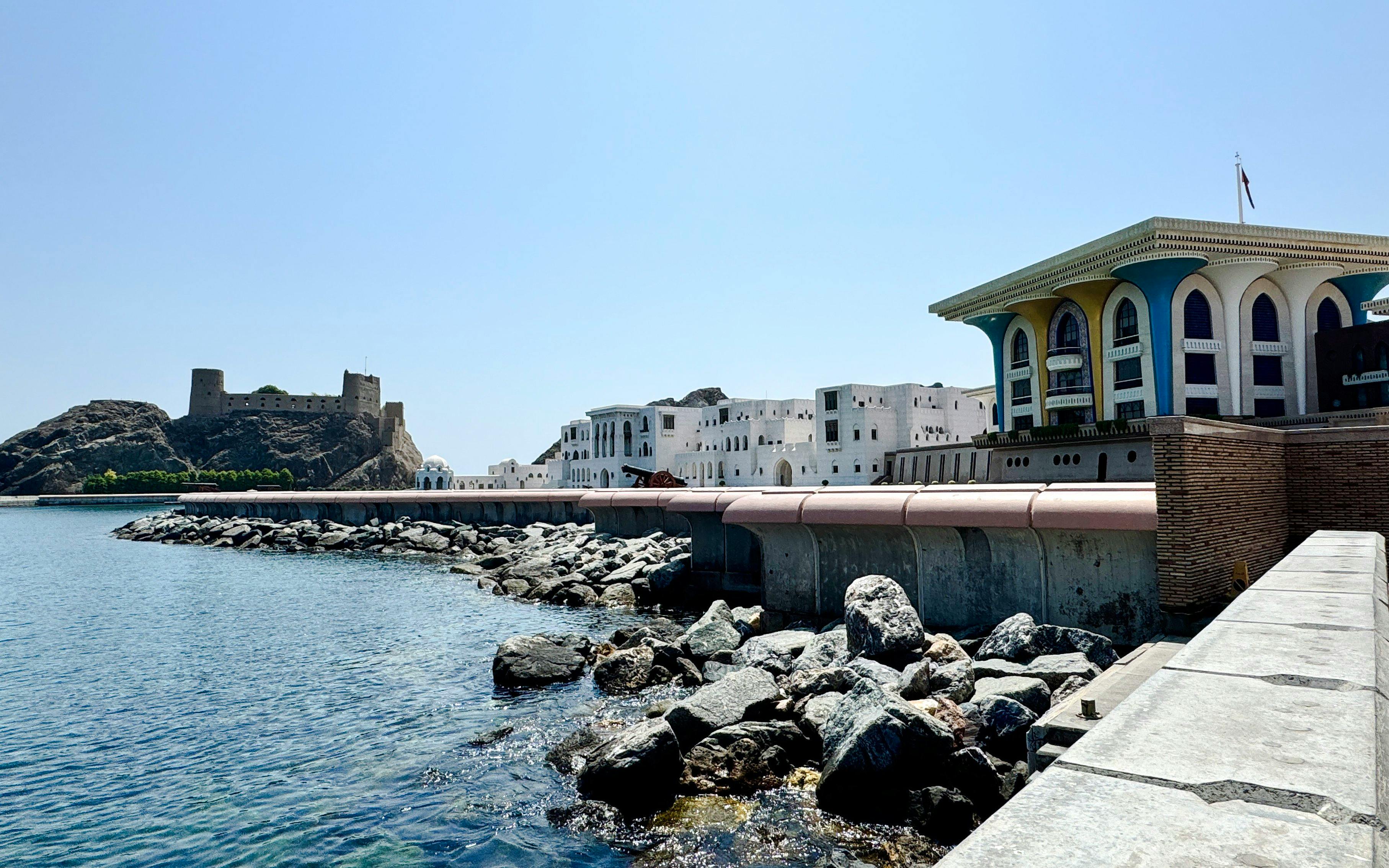 Coastal view of Al Alam Palace and rocky shoreline in Old Muscat, Oman.