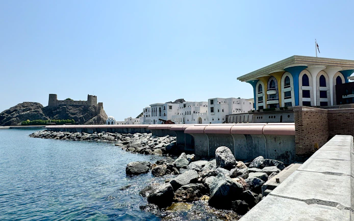 Coastal view of Al Alam Palace and rocky shoreline in Old Muscat, Oman.