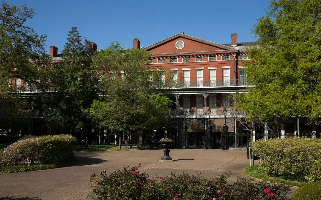 Historic red-brick building with iron balconies in New Orleans, part of the Phantom Ballerina city game.