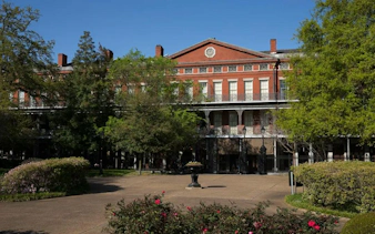 Historic red-brick building with iron balconies in New Orleans, part of the Phantom Ballerina city game.