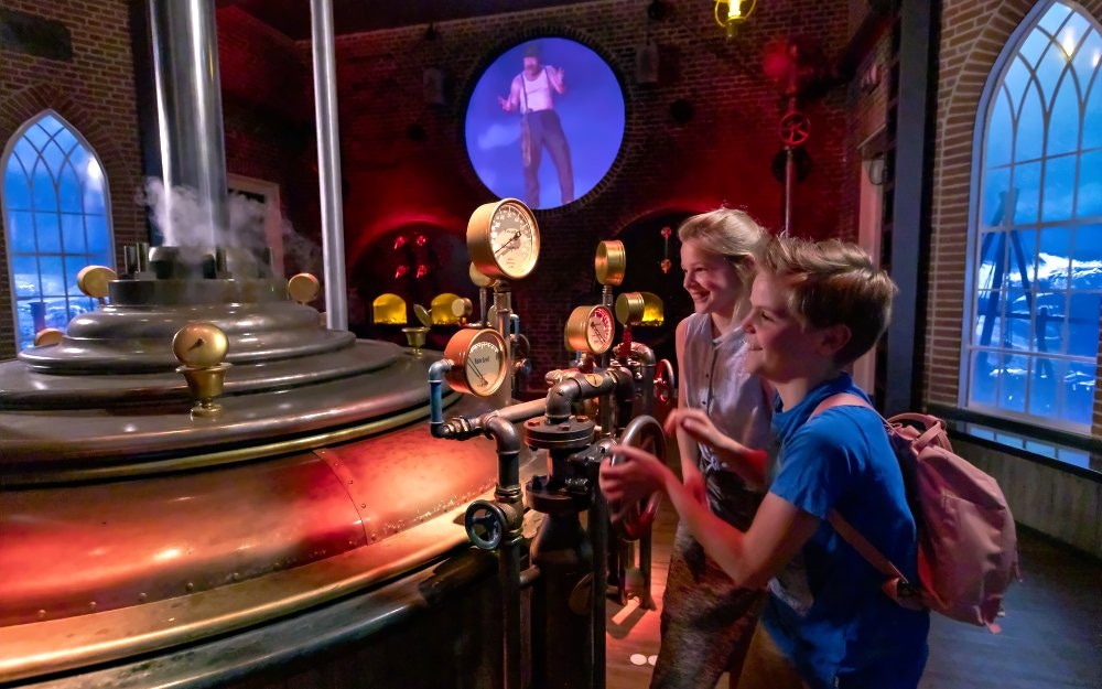 Children exploring interactive steam engine exhibit at Madurodam miniature park.