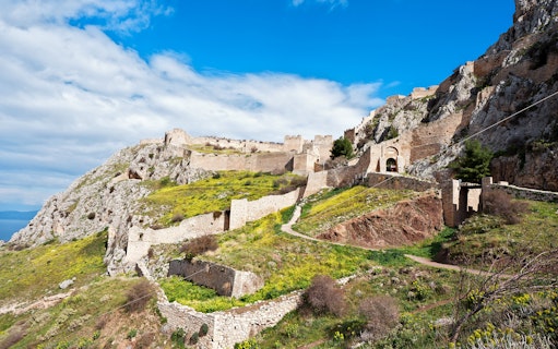 Acrocorinth Fortress on a hilltop with ancient stone walls and scenic landscape, Greece.