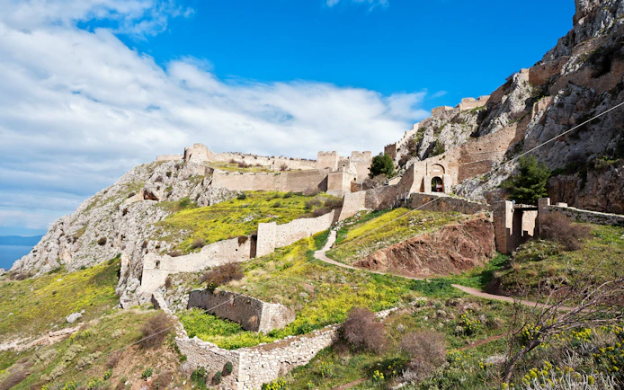Acrocorinth Fortress on a hilltop with ancient stone walls and scenic landscape, Greece.