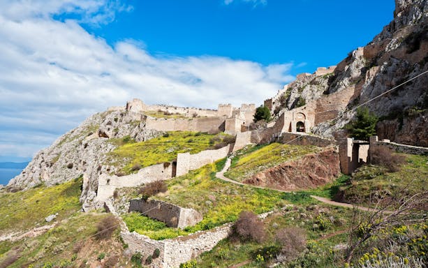Acrocorinth Fortress on a hilltop with ancient stone walls and scenic landscape, Greece.