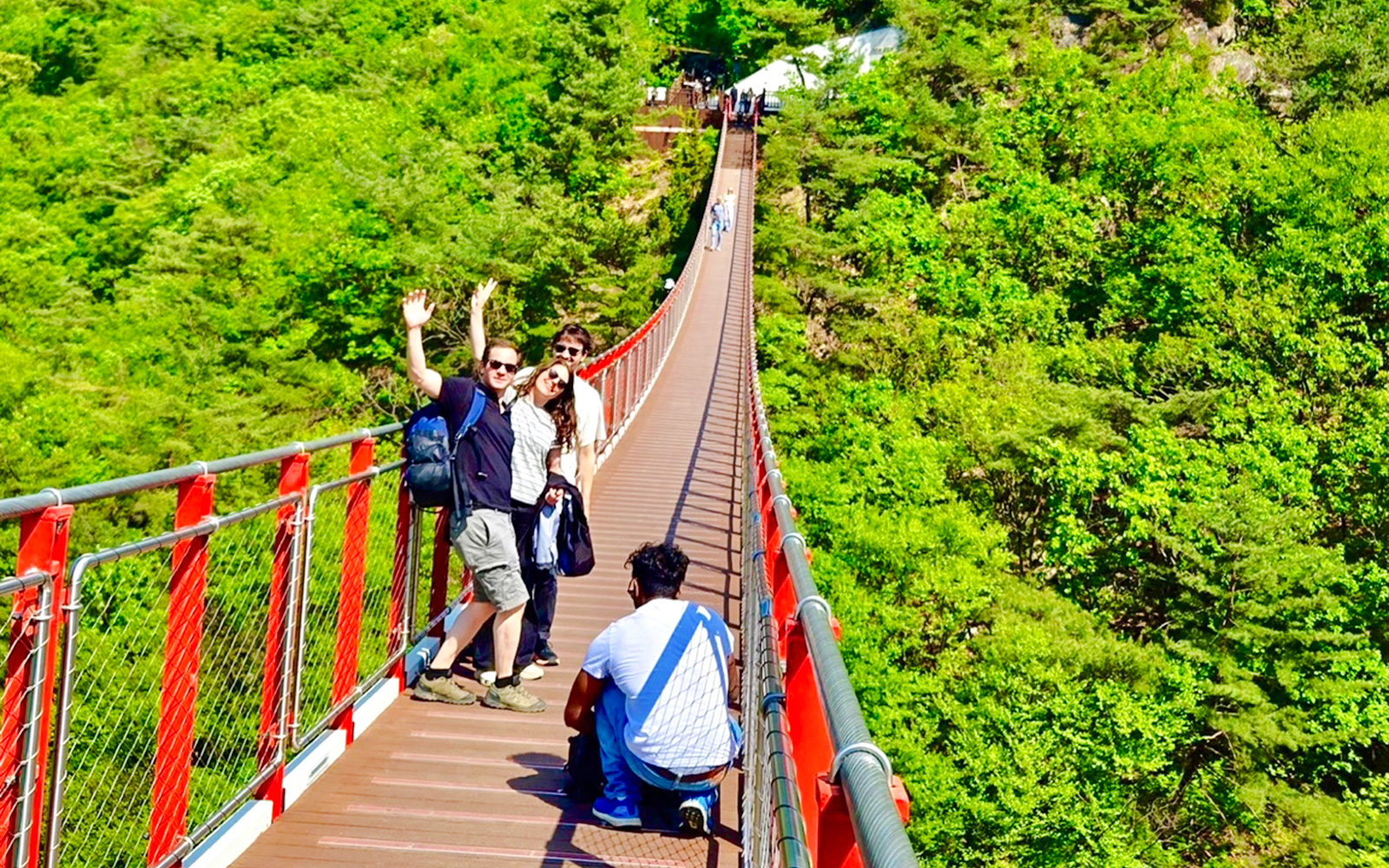 Tourists on a red suspension bridge enjoying mountain views during a DMZ tour from Seoul.