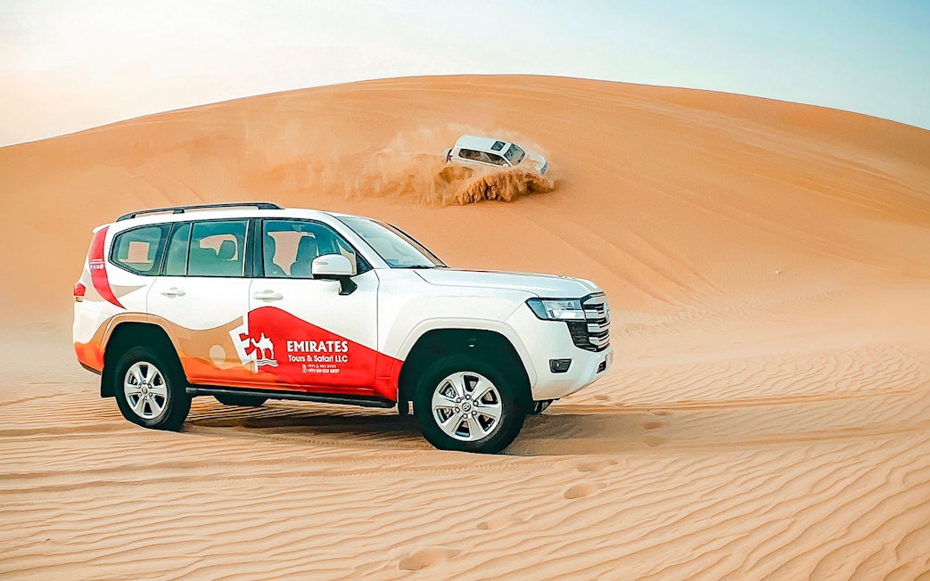 SUVs driving on sand dunes during an overnight desert safari in Abu Dhabi.