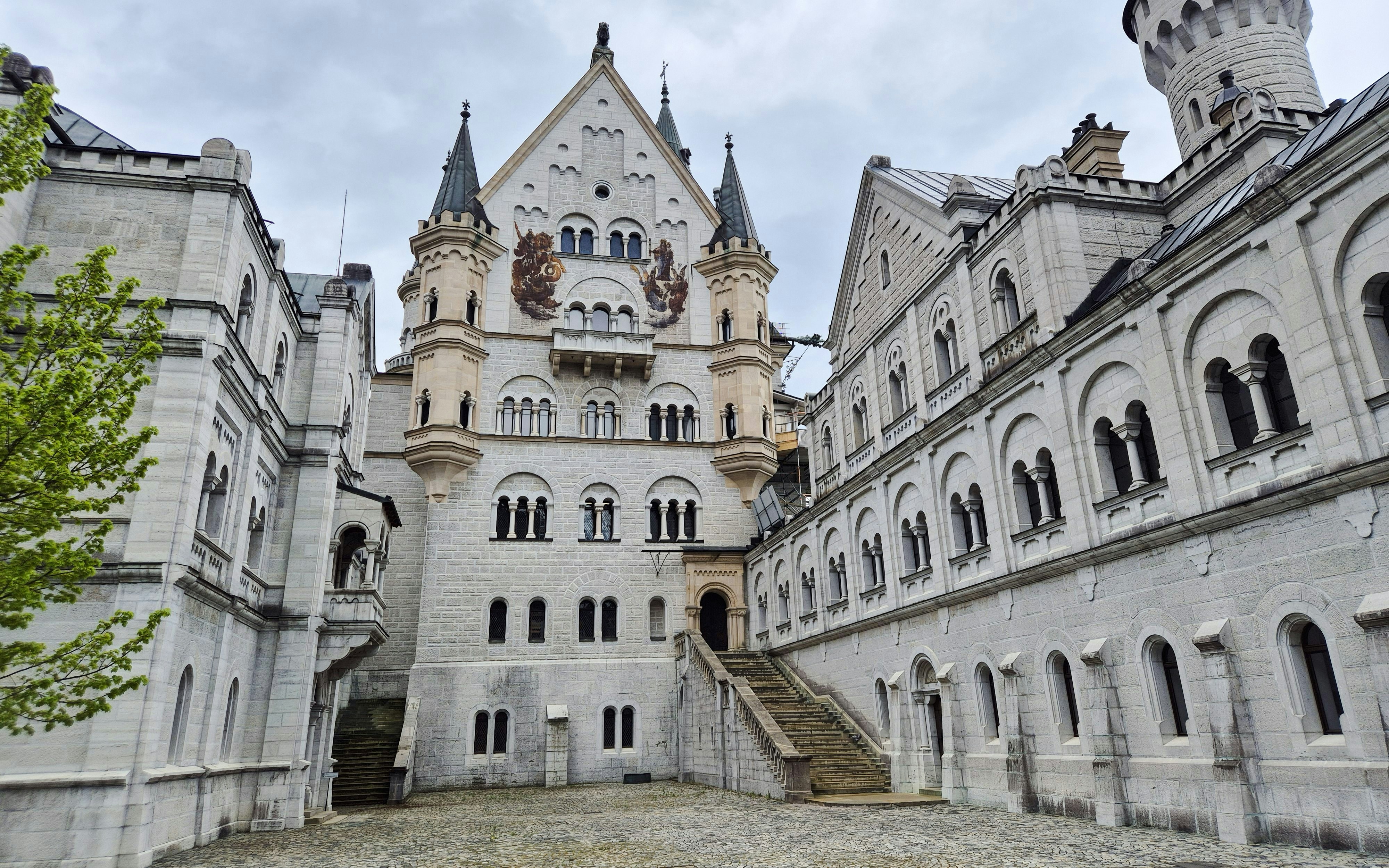 Courtyard view of Neuschwanstein Castle with ornate facade and towers.