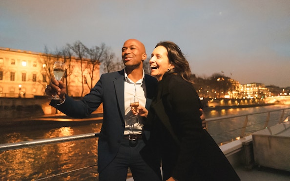 Couple enjoying a boat ride on Bateaux Mouches in Paris at night.