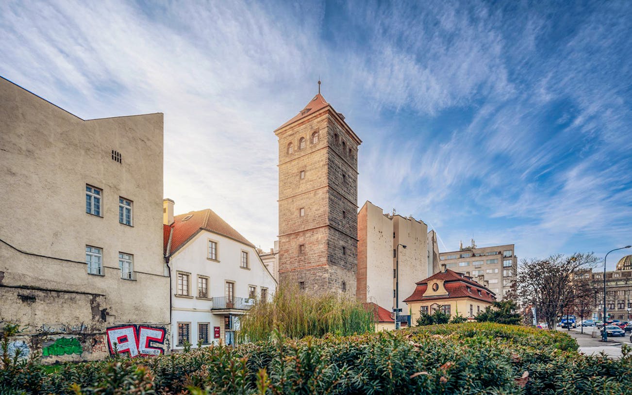 New Mill Water Tower in Prague surrounded by historic buildings and greenery.