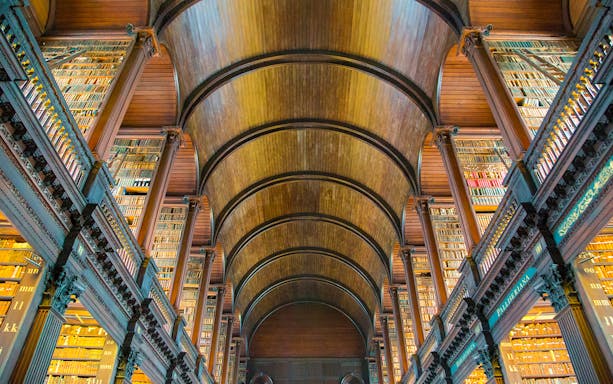 Trinity College Library's Long Room with wooden arches and book-lined shelves, Dublin, Ireland.