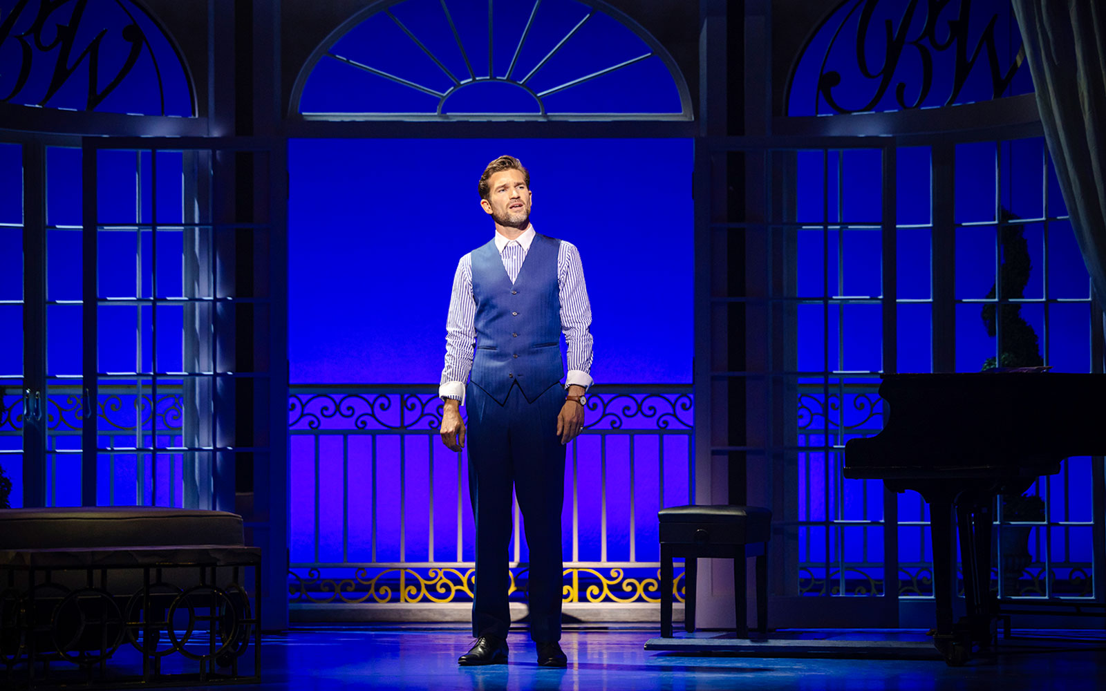 Performer on stage in Pretty Woman The Musical with blue backdrop and piano.
