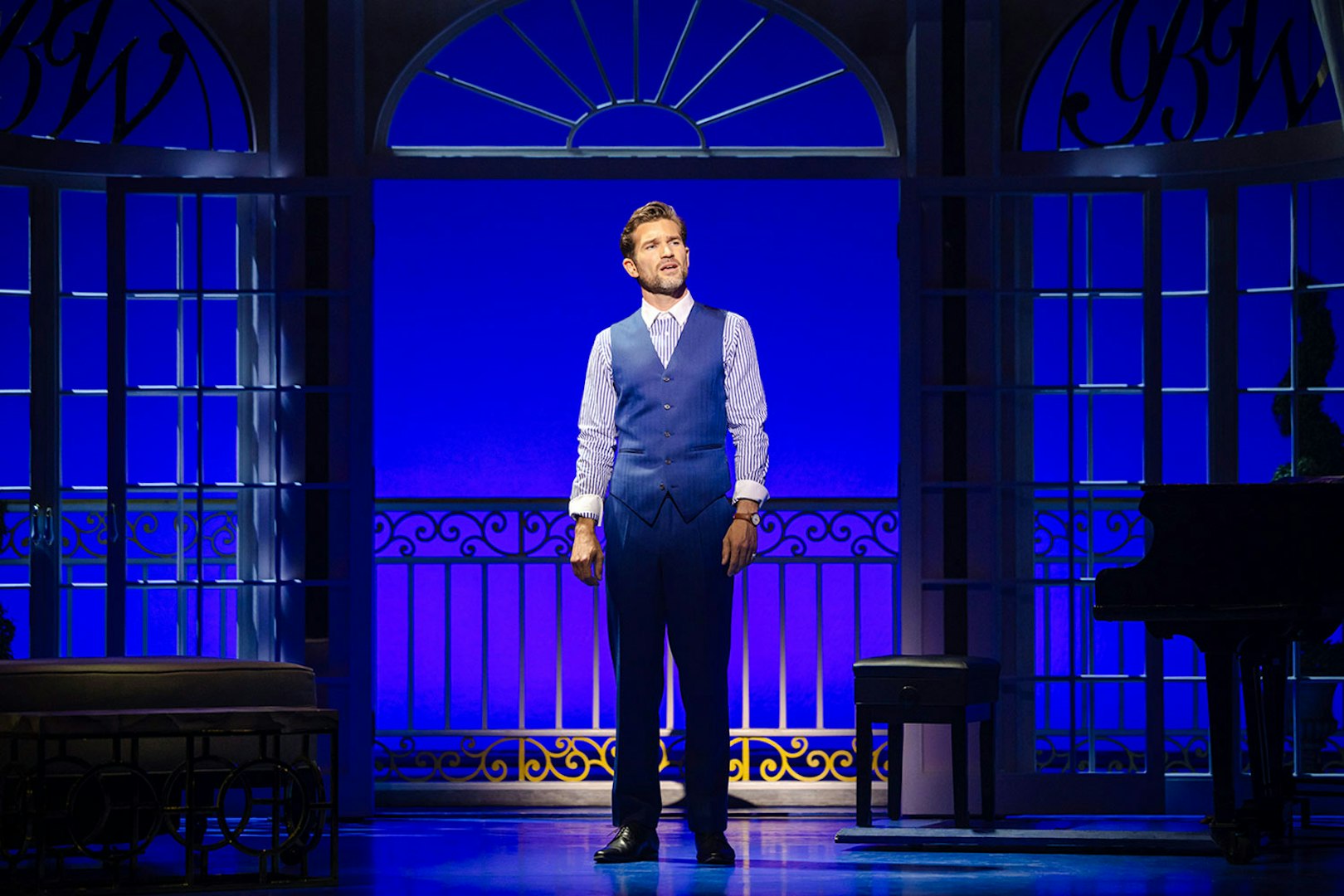 Performer on stage in Pretty Woman The Musical with blue backdrop and piano.
