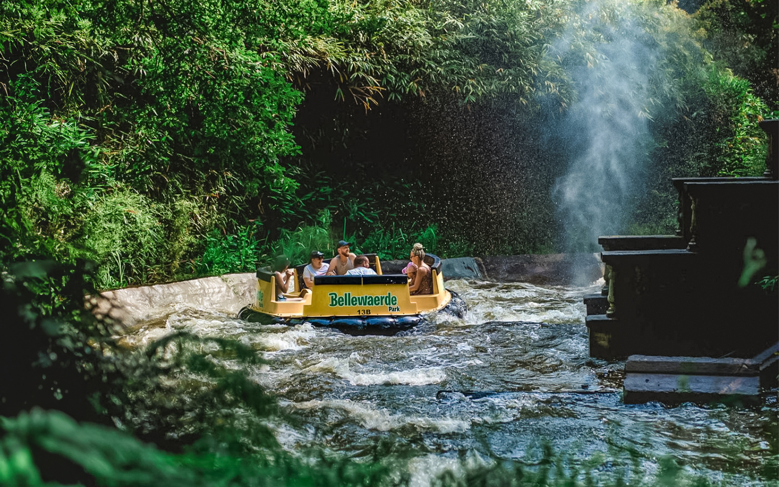Promenade sur la rivière Bengal Rapid dans le parc de Noël de Bellewaerde, avec des décorations festives et des visiteurs sur des radeaux.