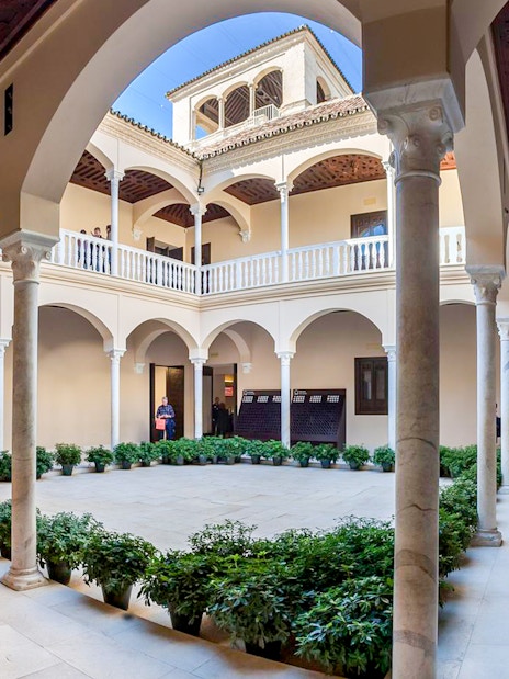 Courtyard of the Picasso Museum in Malaga with arches and potted plants.