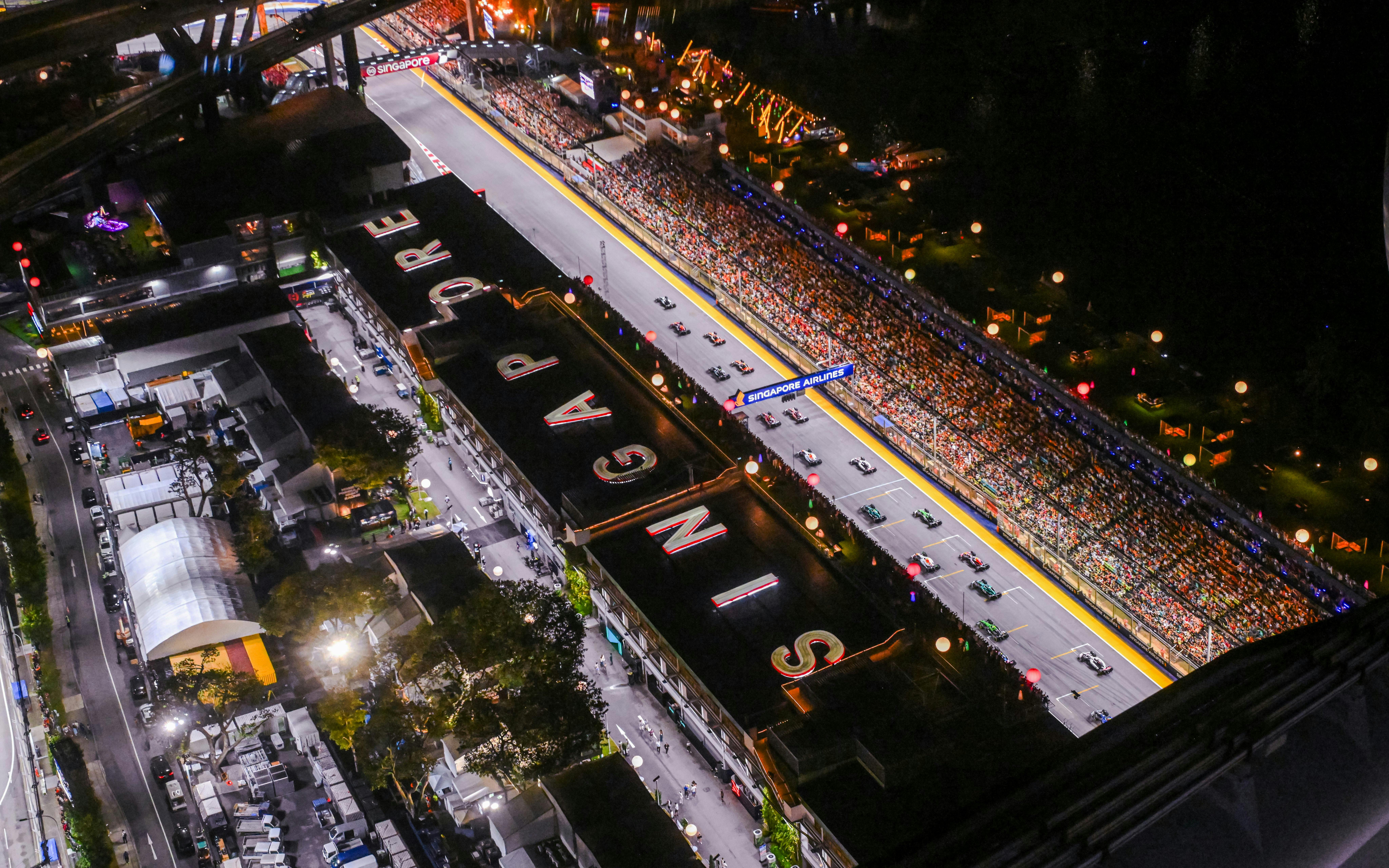Aerial view of Formula 1 Singapore Grand Prix track with cars and audience.