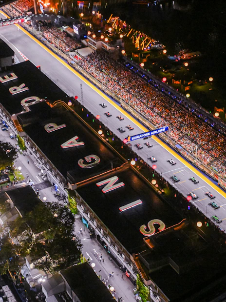Aerial view of Formula 1 Singapore Grand Prix track with cars and audience.