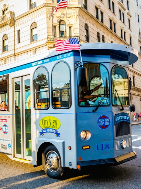 Tourists on a hop-on hop-off trolley in downtown Boston.