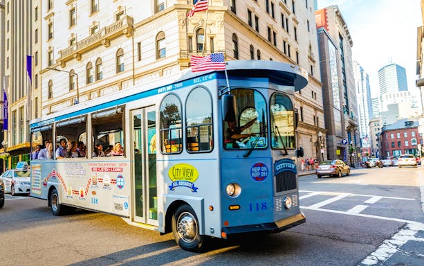 Tourists on a hop-on hop-off trolley in downtown Boston.