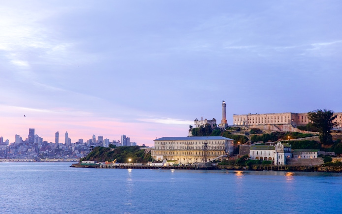 Alcatraz Island with San Francisco skyline at sunset, viewed from the water.