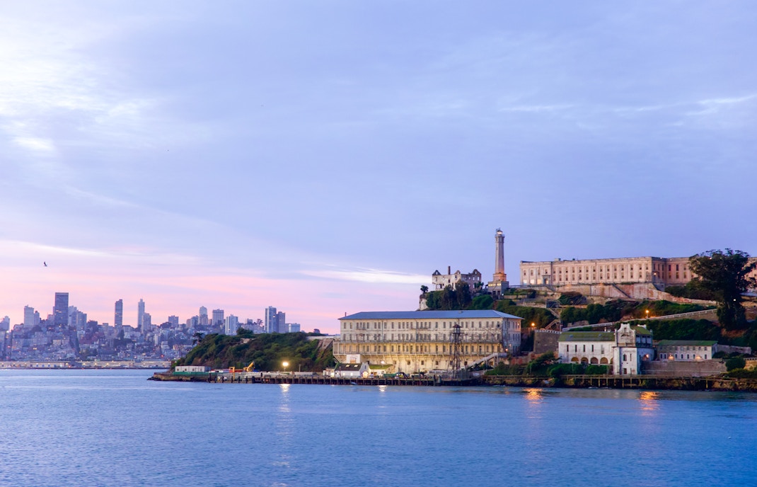 Alcatraz Island with San Francisco skyline at sunset, viewed from the water.