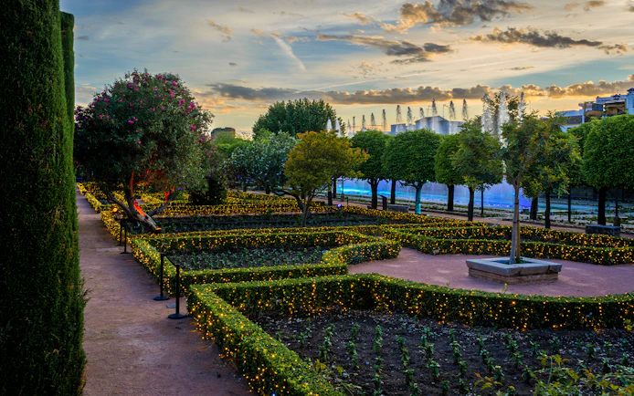 Alcazar of Cordoba garden illuminated at night with fountains and trees.