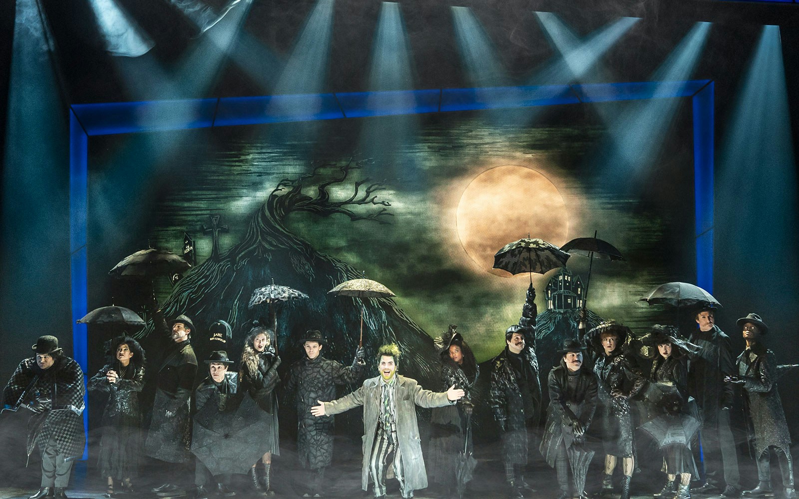 Stage performance of Beetlejuice in West End with cast holding umbrellas.