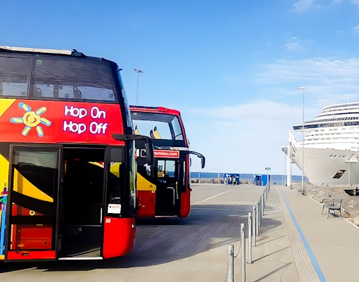 Double-decker bus on New Orleans Hop-On Hop-Off tour passing historic French Quarter buildings.