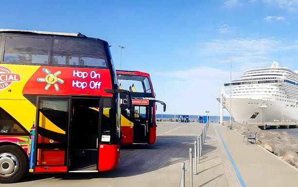 Hop-on hop-off bus near cruise ship docked in Visby, Sweden.