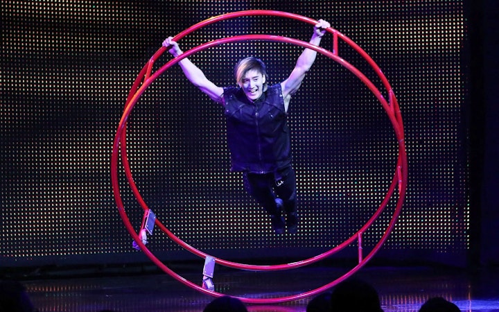 Performer in a red wheel at V - The Ultimate Variety Show.