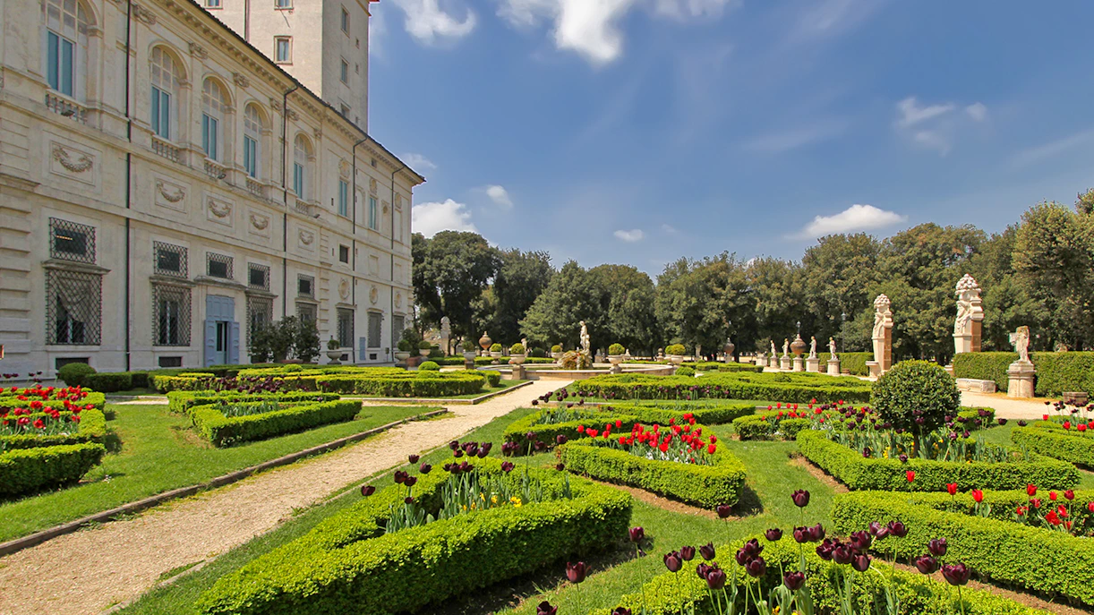 Villa Borghese gardens with manicured hedges and statues in Rome, Italy.