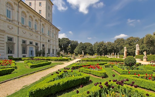 Villa Borghese gardens with manicured hedges and statues in Rome, Italy.