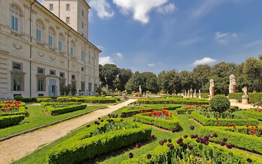 Villa Borghese gardens with manicured hedges and statues in Rome, Italy.