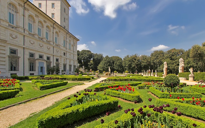 Villa Borghese gardens with manicured hedges and statues in Rome, Italy.