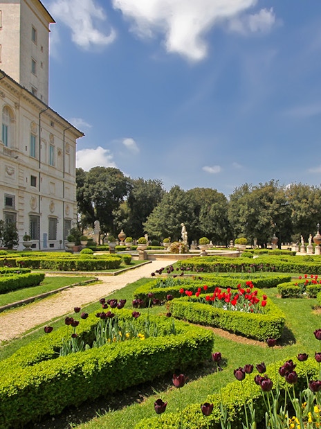 Villa Borghese gardens with manicured hedges and statues in Rome, Italy.