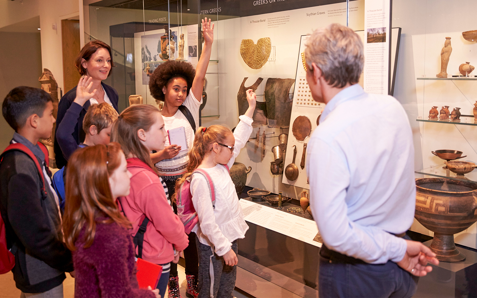 Students examining artifacts in a museum display case.