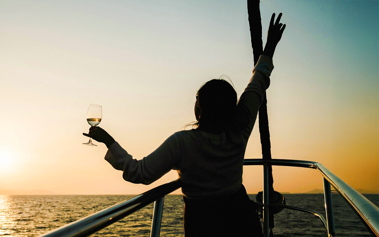 Woman enjoying a drink on a Great Barrier Reef sunset cruise.