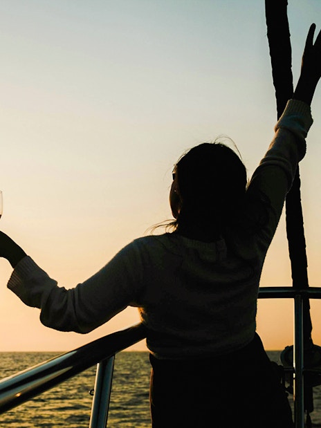 Woman enjoying a drink on a Great Barrier Reef sunset cruise.