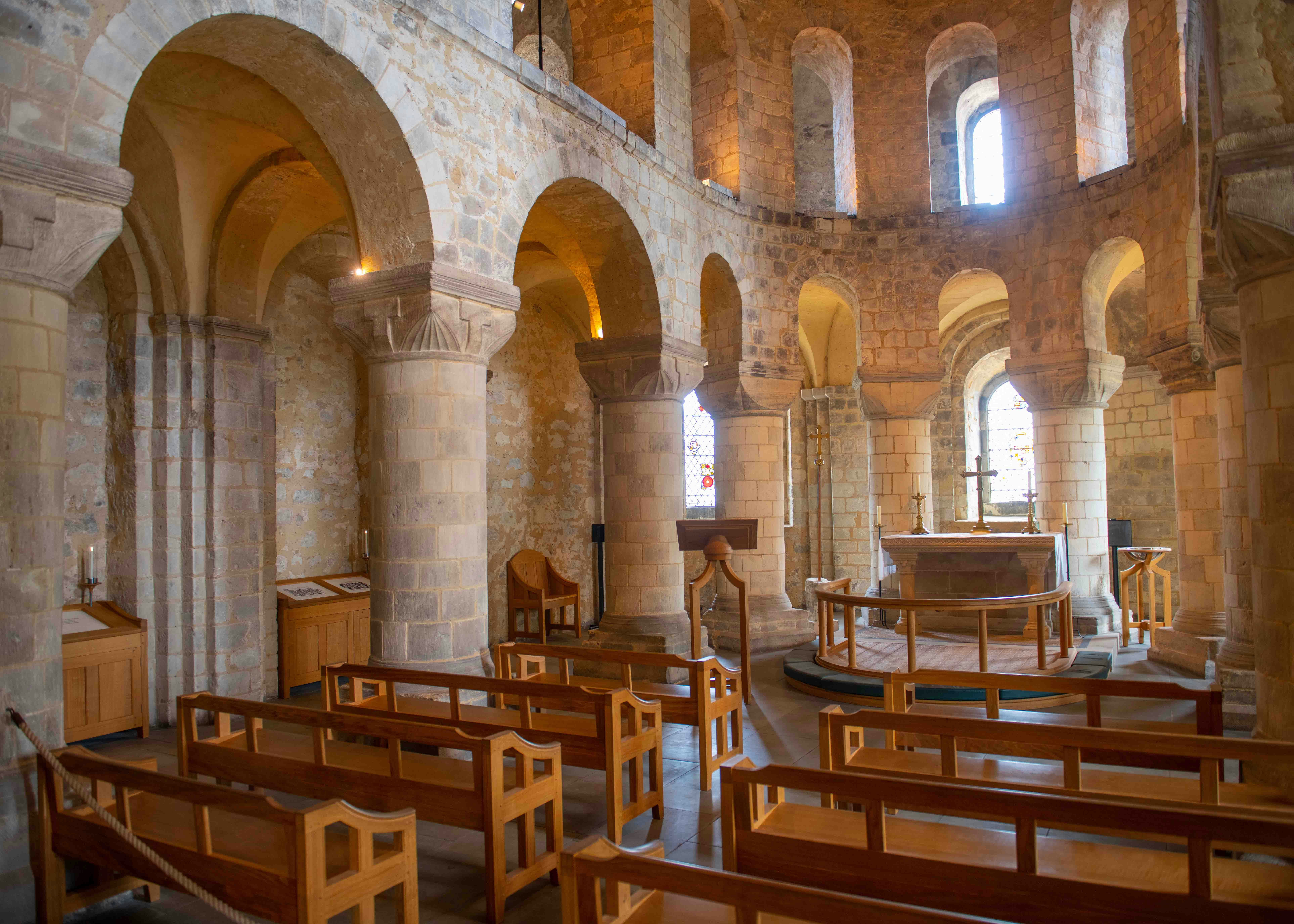 Interior of the Chapel of St. John with stone arches and wooden pews.