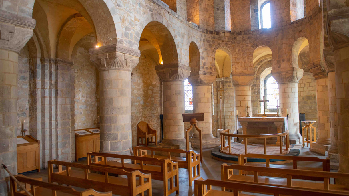 Interior of the Chapel of St. John with stone arches and wooden pews.