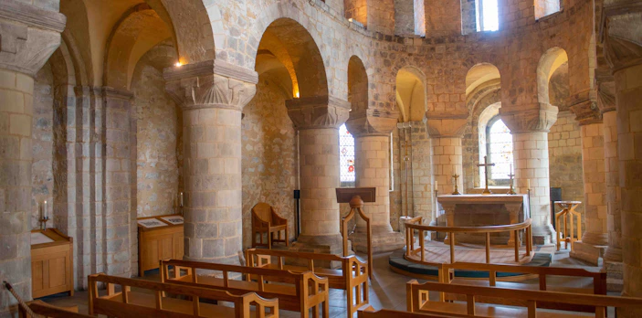 Interior of the Chapel of St. John with stone arches and wooden pews.