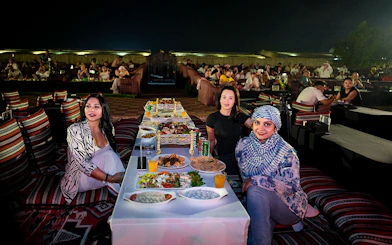 People enjoying evening live performance and dining at a desert safari experience.