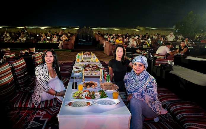 People enjoying evening live performance and dining at a desert safari experience.