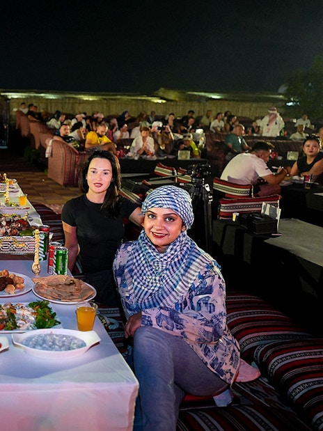 People enjoying evening live performance and dining at a desert safari experience.
