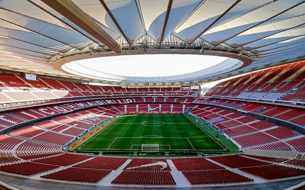 Atlético Madrid stadium interior with empty seats and green field.