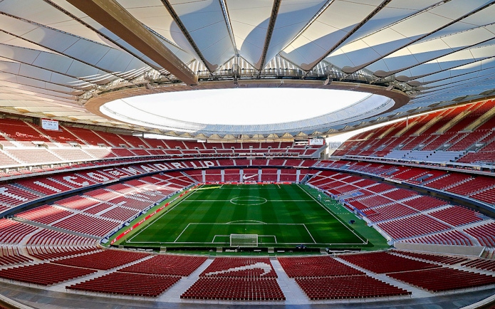 Atlético Madrid stadium interior with empty seats and green field.