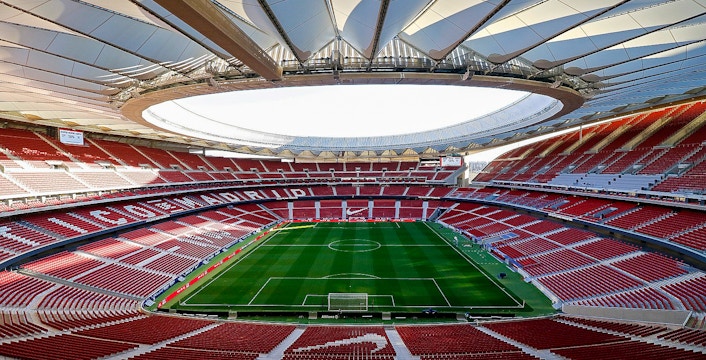 Cívitas Metropolitano Stadium interior with empty red seats and green soccer field.