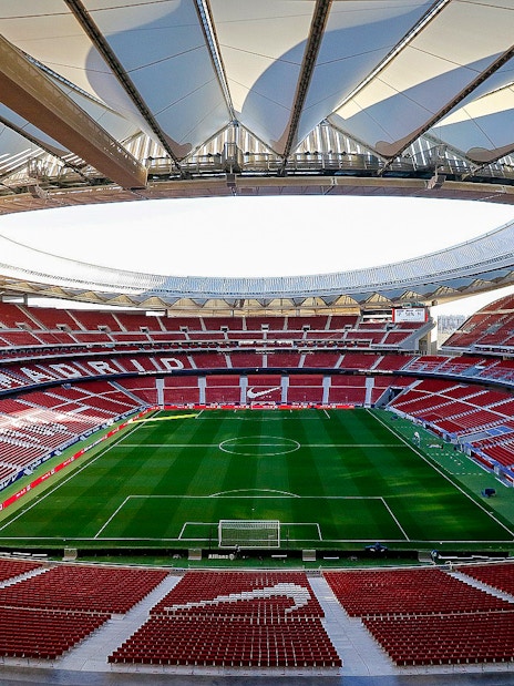 Atlético Madrid stadium interior with empty seats and green field.