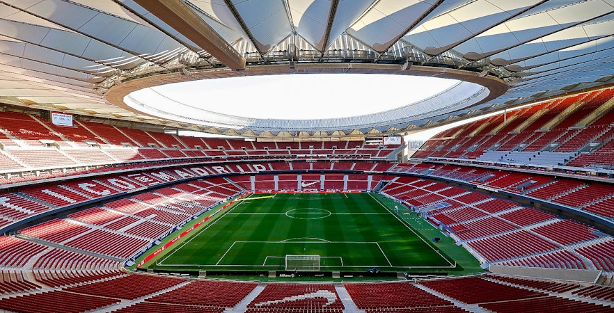 Cívitas Metropolitano Stadium interior with empty red seats and green soccer field.